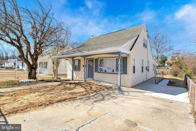 bungalow-style home featuring covered porch, a shingled roof, driveway, and fence