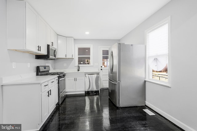 kitchen featuring baseboards, dark wood finished floors, recessed lighting, stainless steel appliances, and white cabinets