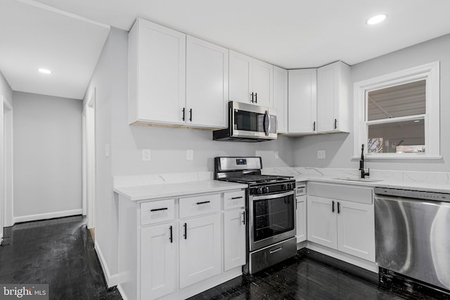 kitchen with dark wood finished floors, white cabinetry, stainless steel appliances, and a sink