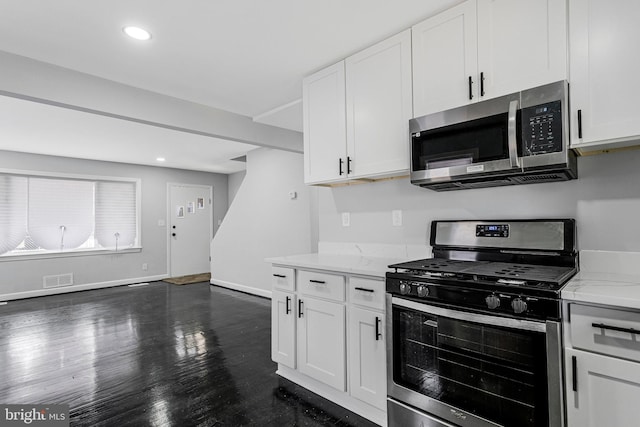 kitchen featuring white cabinetry, stainless steel appliances, baseboards, light stone countertops, and dark wood-style flooring