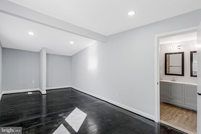 unfurnished bedroom with a sink, baseboards, and dark wood-style flooring