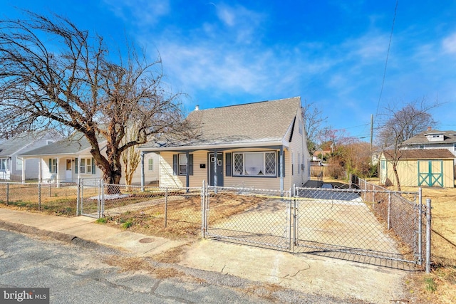 view of front facade featuring an outbuilding, a gate, driveway, a fenced front yard, and a storage shed