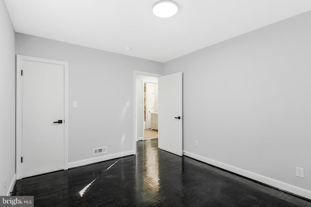 unfurnished bedroom with visible vents, baseboards, and wood finished floors