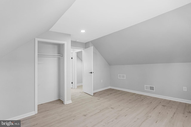 additional living space with vaulted ceiling, light wood-style flooring, baseboards, and visible vents