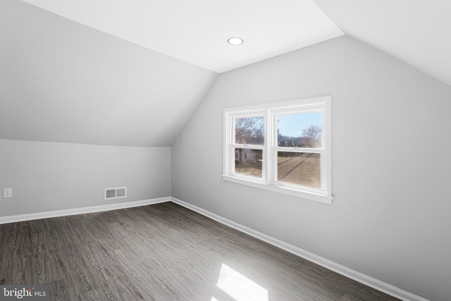 bonus room with visible vents, lofted ceiling, baseboards, and dark wood-style flooring