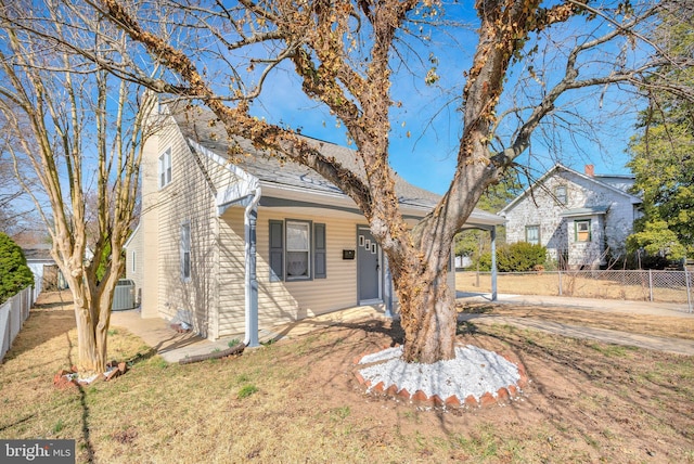 view of front of property with a front yard, central air condition unit, and fence