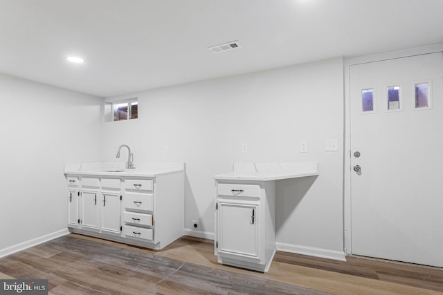 clothes washing area featuring wood finished floors, baseboards, visible vents, recessed lighting, and a sink