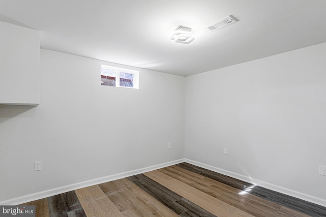 below grade area with visible vents, baseboards, and wood finished floors