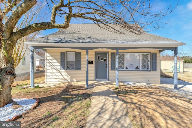 bungalow featuring fence, covered porch, and a shingled roof