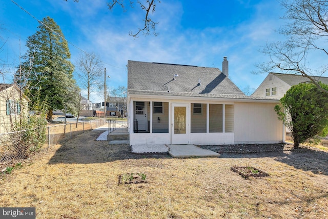 rear view of house with a shingled roof, a chimney, a yard, and fence