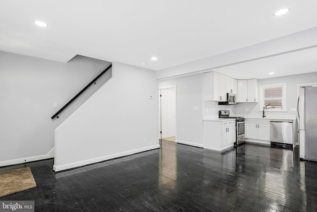 unfurnished living room with dark wood finished floors, recessed lighting, baseboards, and a sink