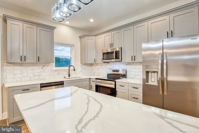 kitchen with decorative backsplash, gray cabinetry, stainless steel appliances, and a sink