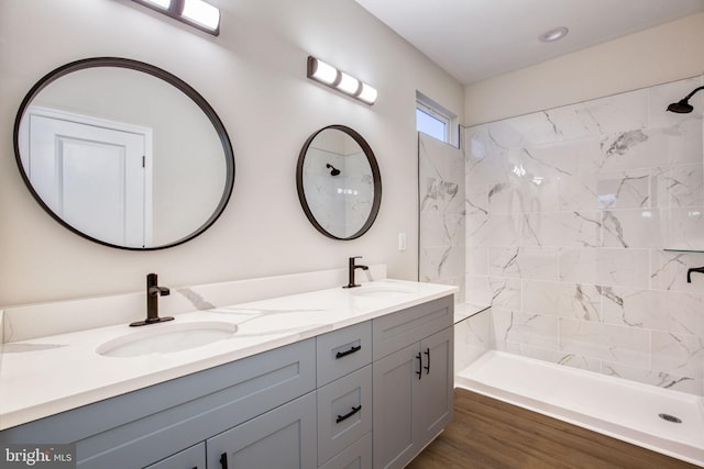 full bath with double vanity, tiled shower, and a sink