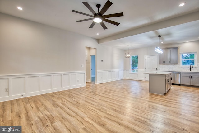 kitchen with dishwasher, open floor plan, gray cabinets, and a sink