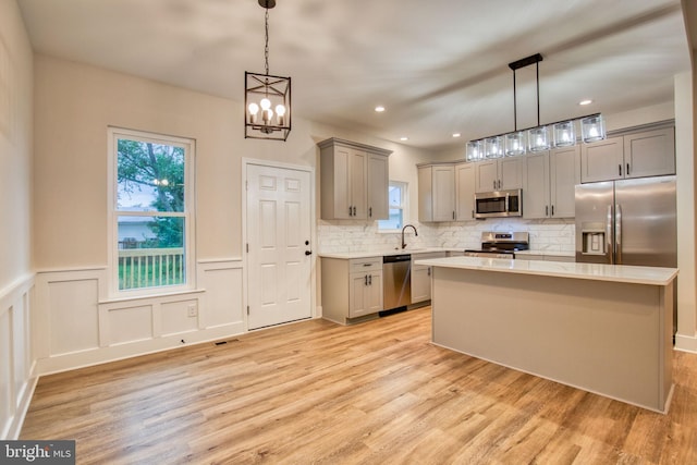 kitchen with light wood finished floors, gray cabinets, a sink, stainless steel appliances, and light countertops