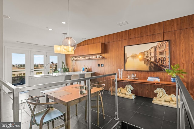 dining space with tile patterned floors, recessed lighting, and wood walls