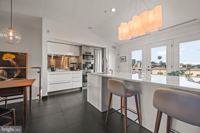 kitchen featuring a sink, hanging light fixtures, vaulted ceiling, white cabinets, and modern cabinets