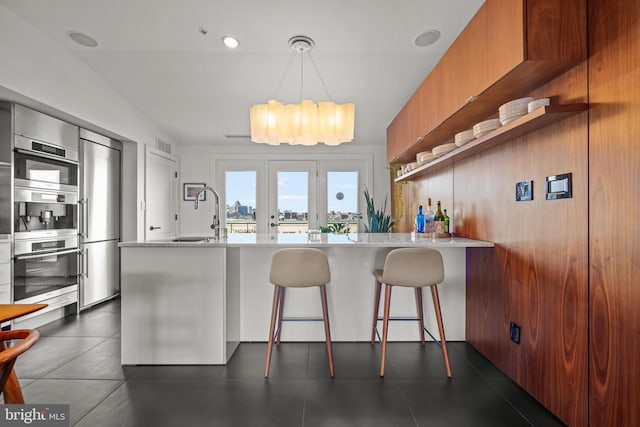 kitchen featuring brown cabinetry, open shelves, a sink, light countertops, and modern cabinets