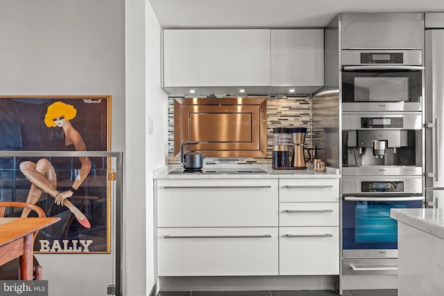 kitchen with black electric stovetop, double oven, decorative backsplash, white cabinets, and modern cabinets