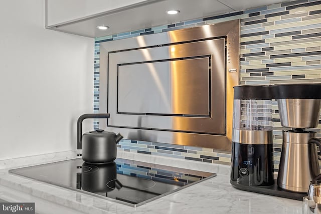 room details featuring stone countertops, black electric cooktop, and tasteful backsplash