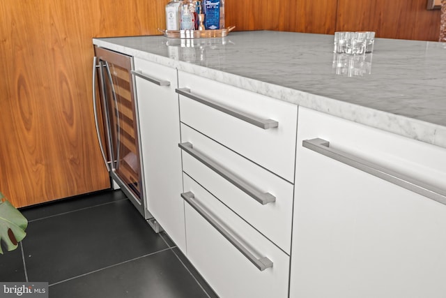 details featuring light stone counters, beverage cooler, white cabinets, and a dry bar