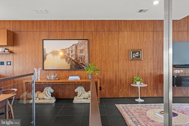 interior space with visible vents, wood walls, and dark tile patterned flooring