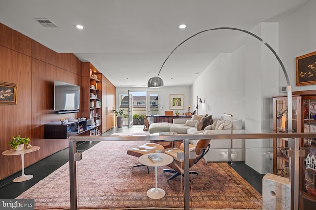 living room featuring wooden walls, built in features, recessed lighting, and visible vents