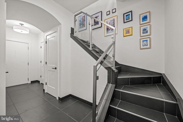 staircase with tile patterned flooring, baseboards, and arched walkways