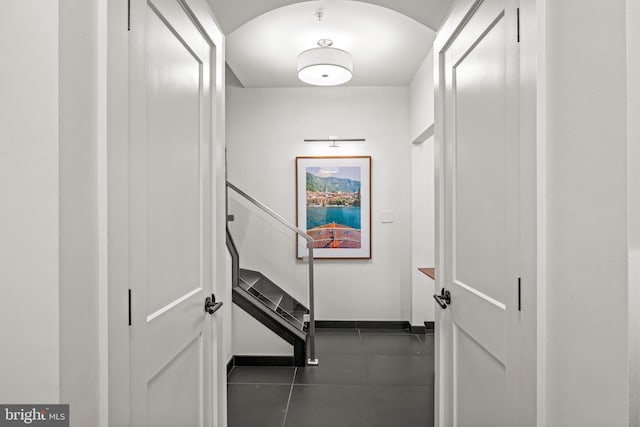 corridor with baseboards, arched walkways, and stairs