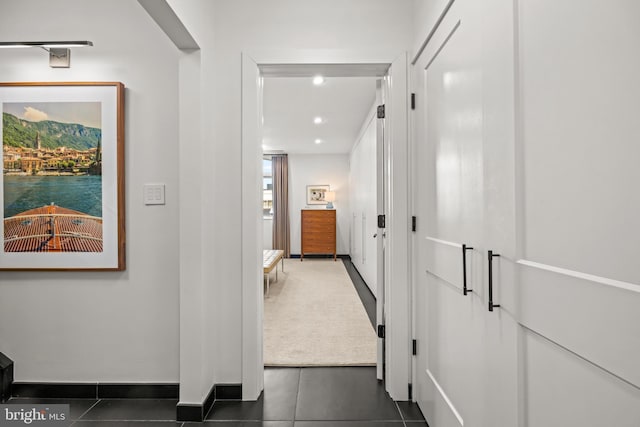 hall featuring dark tile patterned floors, recessed lighting, and baseboards