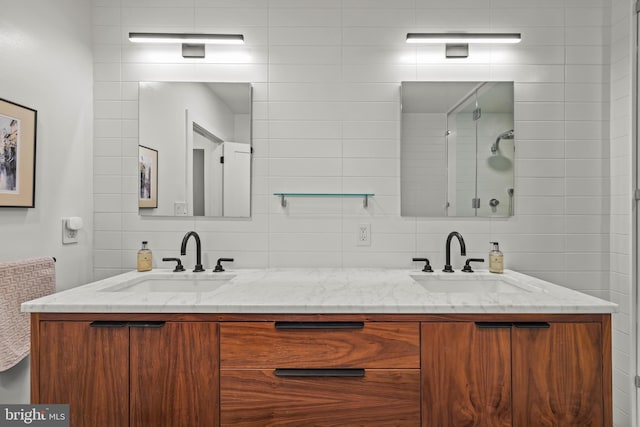 bathroom featuring double vanity, backsplash, tiled shower, and a sink