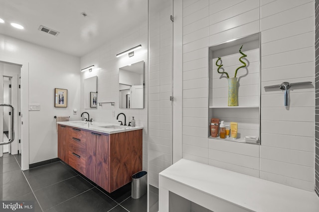 bathroom with a sink, visible vents, tile walls, and tile patterned flooring