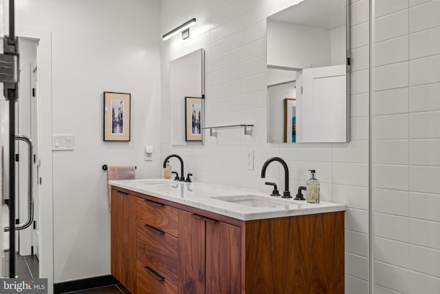 bathroom featuring a sink, decorative backsplash, tile walls, and double vanity