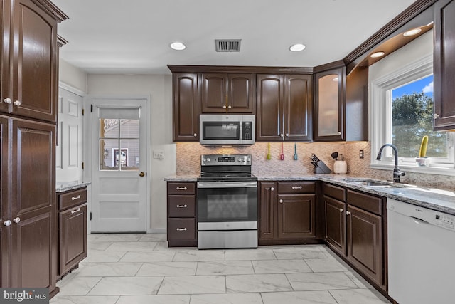 kitchen with a sink, marble finish floor, appliances with stainless steel finishes, and dark brown cabinetry