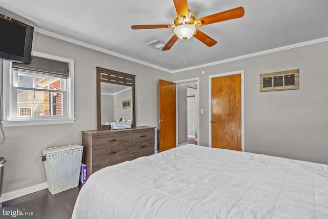 bedroom featuring dark wood-style floors, visible vents, baseboards, and ornamental molding