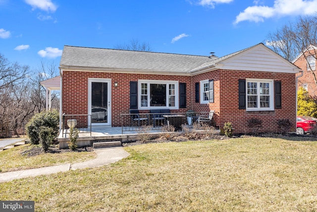 view of front facade with a front lawn, brick siding, and a shingled roof