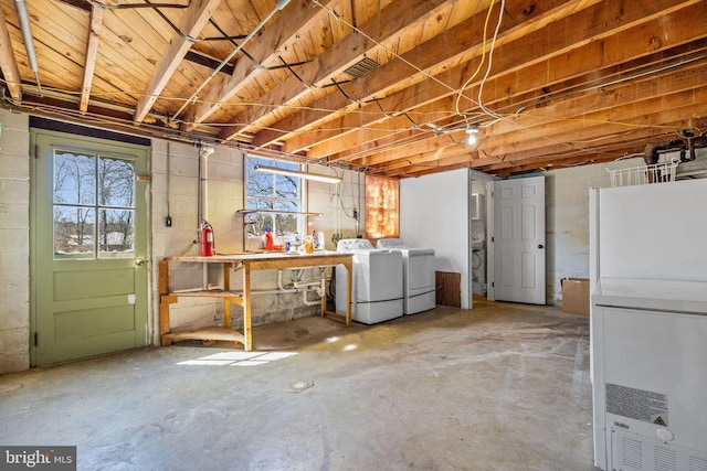 below grade area with concrete block wall, plenty of natural light, and washing machine and dryer