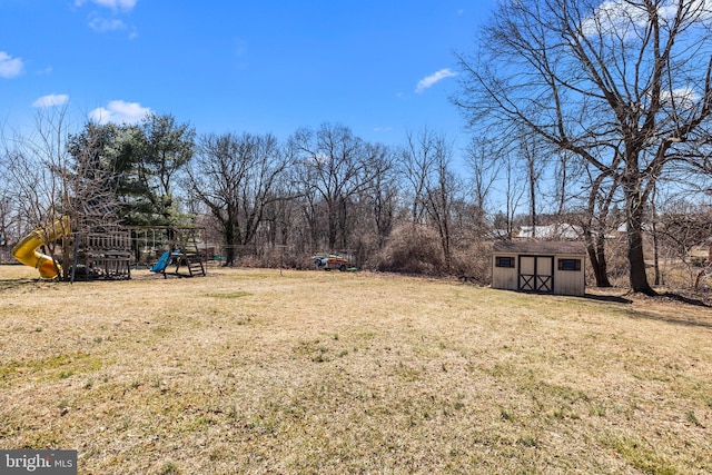 view of yard featuring a storage shed, a playground, and an outdoor structure