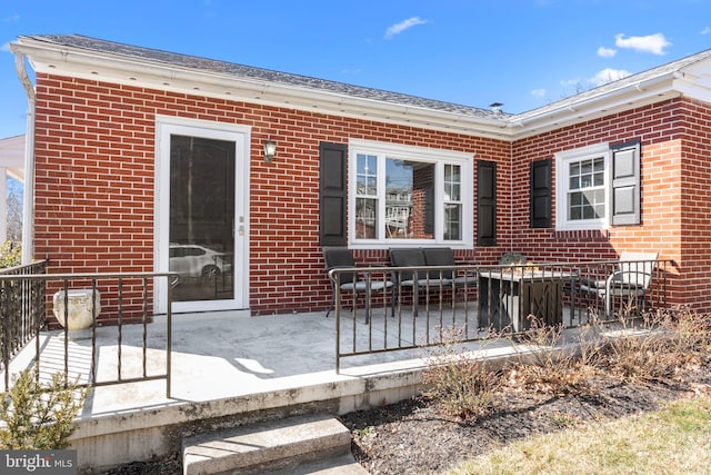 rear view of property featuring a patio and brick siding