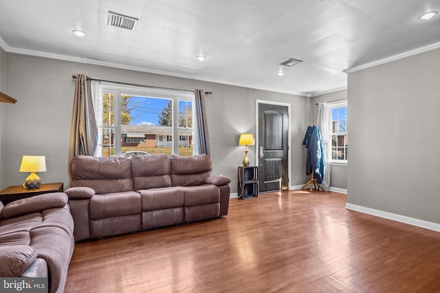 living room with baseboards, wood finished floors, visible vents, and a healthy amount of sunlight