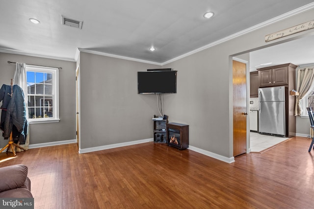 living area with light wood-type flooring, baseboards, visible vents, and ornamental molding