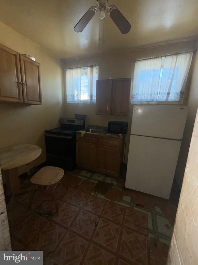 kitchen featuring black microwave, freestanding refrigerator, electric range, a ceiling fan, and a sink