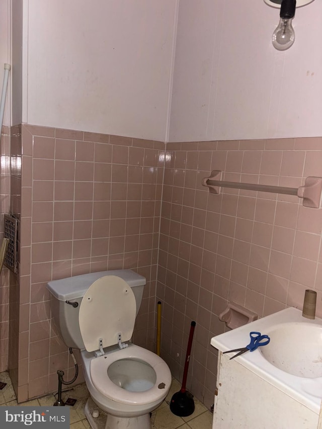 bathroom with tile patterned flooring, toilet, and tile walls