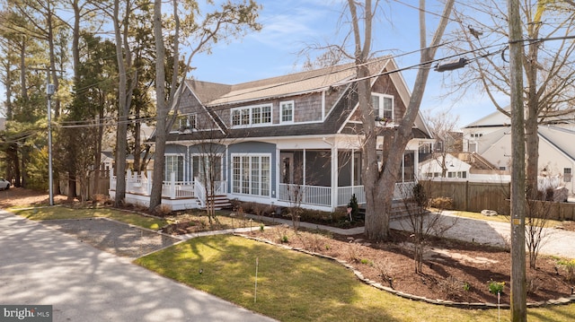 shingle-style home featuring fence, a sunroom, and a shingled roof