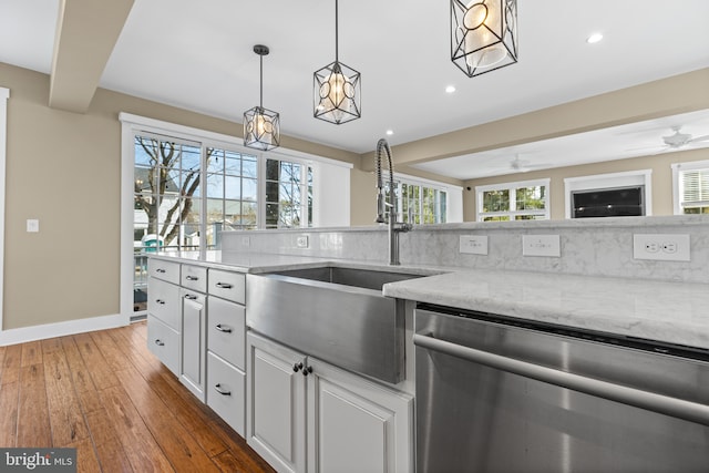 kitchen featuring light stone counters, a sink, wood-type flooring, stainless steel dishwasher, and tasteful backsplash