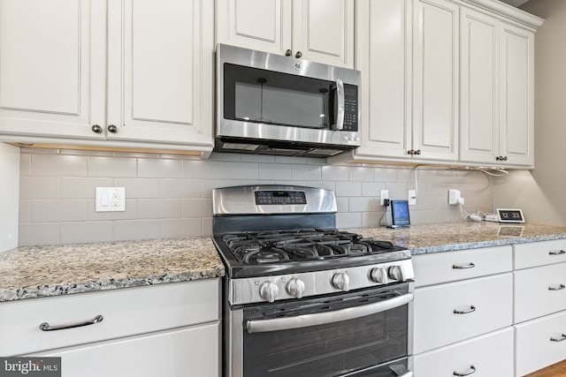 kitchen with stainless steel appliances, white cabinets, and decorative backsplash