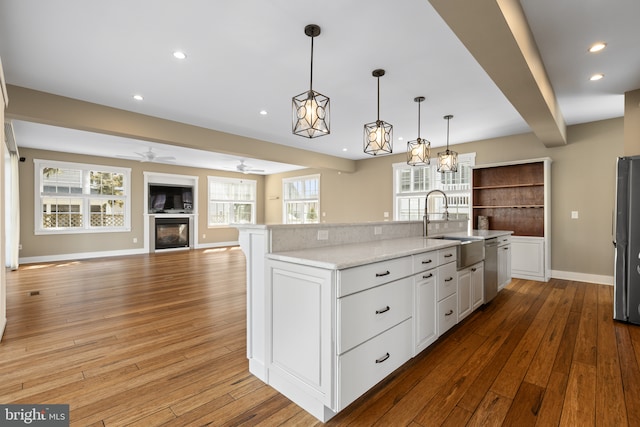 kitchen with a sink, appliances with stainless steel finishes, hardwood / wood-style floors, and white cabinetry