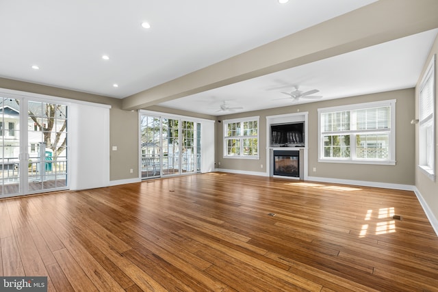 unfurnished living room featuring hardwood / wood-style floors, a glass covered fireplace, recessed lighting, and baseboards