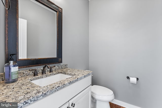 bathroom with baseboards, toilet, wood finished floors, and vanity