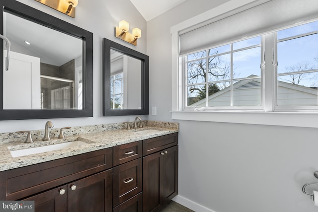 full bathroom with lofted ceiling, double vanity, a shower stall, and a sink